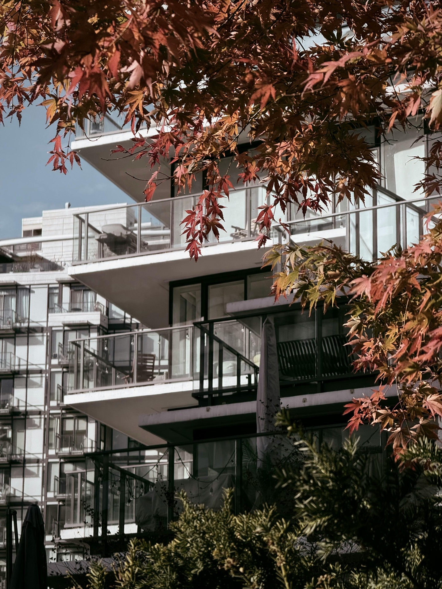 Stacked glass-railing balconies on a multi-family residential tower, with sealant joints, slab edges, and railing anchors visible across multiple floors under inspection scope
